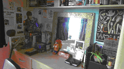 a bedroom wall with many posters, a desk, and many books